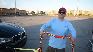 A person holding the BLINCOO tug rope beside a black SUV